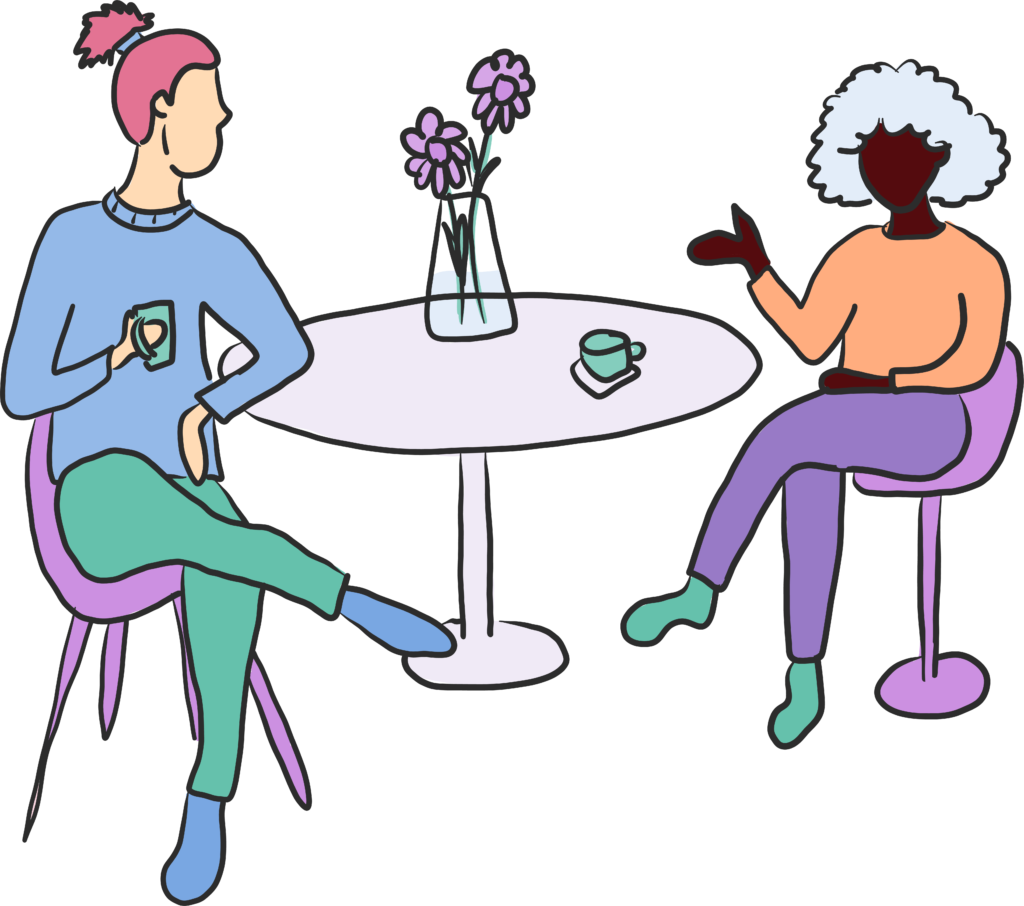 2 people sitting at a cafe style table, having a cup of tea and a chat. 1 person has a light skin tone and pink hair worn in a top knot. The other has a dark skin tone and bushy grey hair.