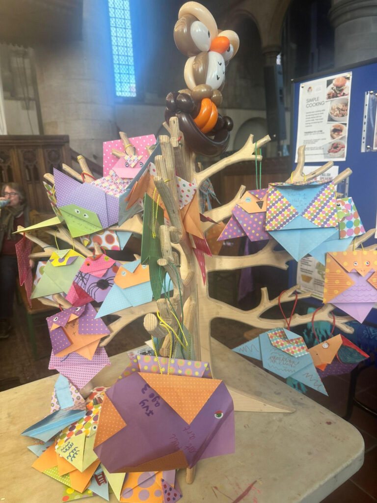MindWell's owl tree - a wooden tree model with lots of colourful paper owls hanging from it and a balloon owl perched at the top.