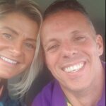 Jill and Michael are heads togehter as they smile at the camera. They both have light skin tones, Jill has jaw length blonde hair and blue top, Michael has short hair and purple top.